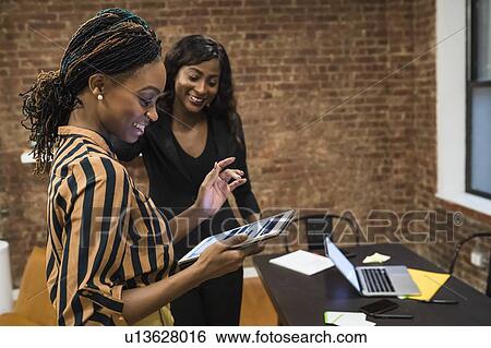 Businesswomen using digital tablet, laptop and cellphone on desk View Large Photo Image Stock Photograph - Businesswomen using digital tablet, laptop and cellphone on desk. Fotosearch