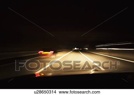 Picture - Car driving on road at night. Fotosearch