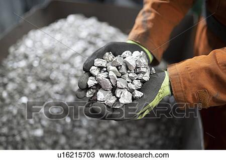 Stock Image - Close up of worker holding titanium sample in crushing plant in titanium recycling plant. Fotosearch
