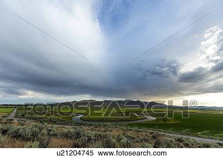 Stock Photography - Cloudscape over river through fields in Picabo, Idaho, USA. Fotosearch