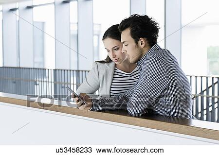 Stock Image - Colleagues using smartphone in office corridor. Fotosearch