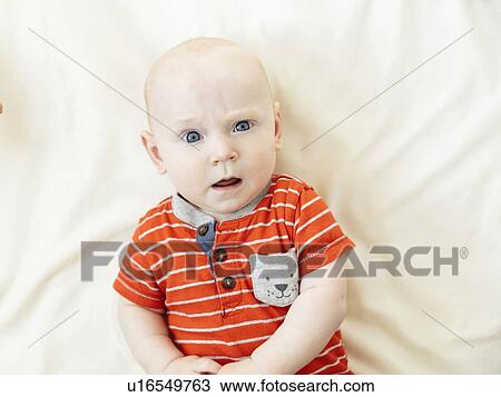 Stock Image - Confused baby boy lying on bed. Fotosearch