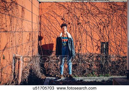 Stock Image - Cool young woman standing on urban wall with eyes closed, portrait. Fotosearch