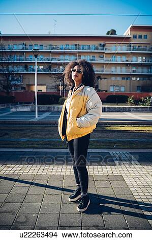 Cool young woman wearing sunglasses standing on urban sidewalk, portrait View Large Photo Image Picture - Cool young woman wearing sunglasses standing on urban sidewalk, portrait. Fotosearch