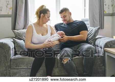Couple cradling baby on sofa View Large Photo Image Stock Image - Couple cradling baby on sofa. Fotosearch