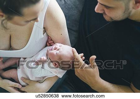 Stock Photo - Couple cradling baby on sofa. Fotosearch