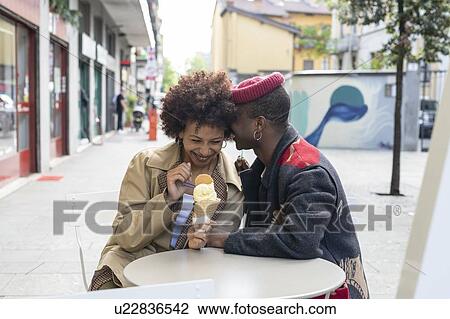 Stock Image - Couple enjoying ice-cream at sidewalk cafe, Milan, Italy. Fotosearch