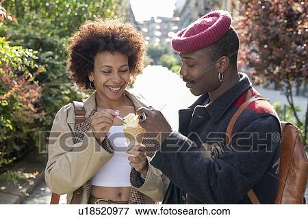 Stock Photo - Couple enjoying ice-cream on street, Milan, Italy. Fotosearch