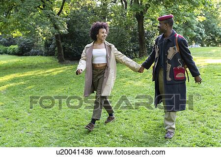 Stock Photograph - Couple holding hands walking in park, Milan, Italy. Fotosearch