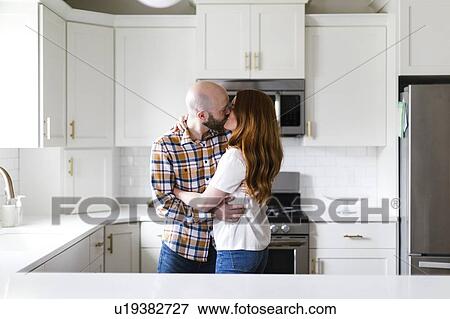 Couple kissing in kitchen View Large Photo Image Stock Photo - Couple kissing in kitchen. Fotosearch