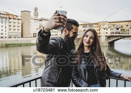 Stock Image - Couple taking selfie on bridge, Ponte Vecchio, Firenze, Toscana, Italy. Fotosearch