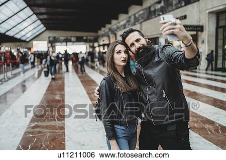 Couple taking selfie with smartphone in station View Large Photo Image Stock Photograph - Couple taking selfie with smartphone in station. Fotosearch