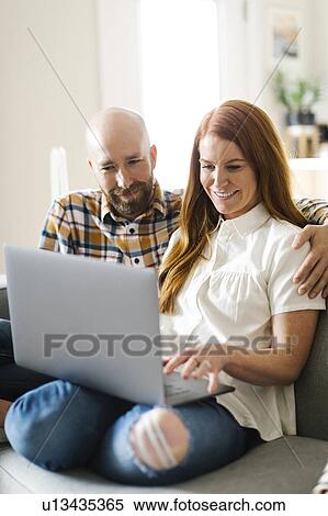 Stock Photography - Couple using laptop on sofa. Fotosearch