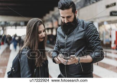 Picture - Couple using smartphone in station. Fotosearch