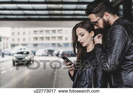 Couple using smartphone outside station View Large Photo Image Stock Photo - Couple using smartphone outside station. Fotosearch