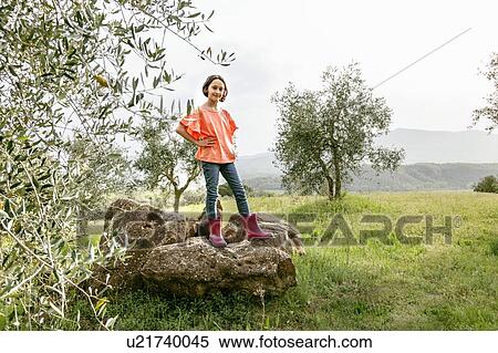 Stock Photography - Cute girl with bobbed hair standing on rock in scenic field landscape, portrait, Citta della Pieve, Umbria, Italy. Fotosearch
