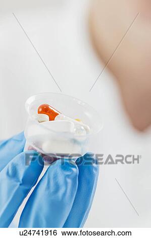 Doctor's hand in a glove holding graduated cup with pills View Large Photo Image Stock Photograph - Doctor's hand in a glove holding graduated cup with pills. Fotosearch