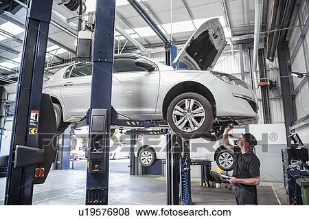 Stock Photo - Engineer checking car on ramp in car service centre. Fotosearch