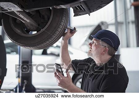 Picture - Engineer checking car tyre during service in car service centre. Fotosearch