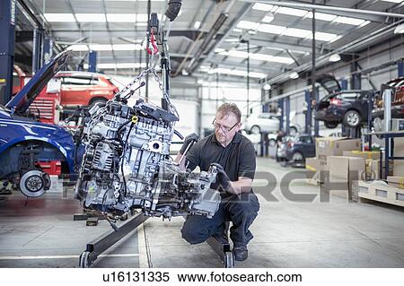 Stock Photography - Engineer with car engine in car service centre. Fotosearch