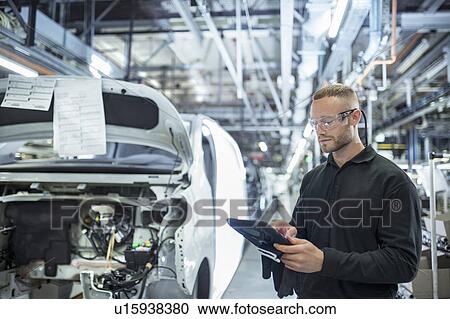 Stock Image - Engineer with digital tablet on production line in car factory. Fotosearch