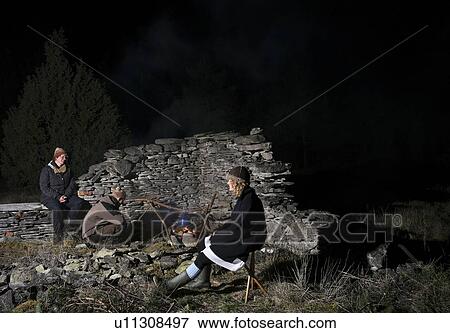 Stock Photo - Family of three relaxing by campfire in forest at night, Fr, Gotlands Lan, Sweden. Fotosearch