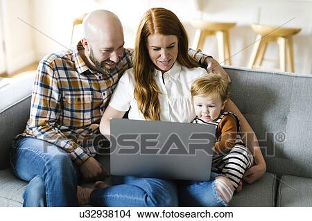 Picture - Family using laptop on sofa. Fotosearch