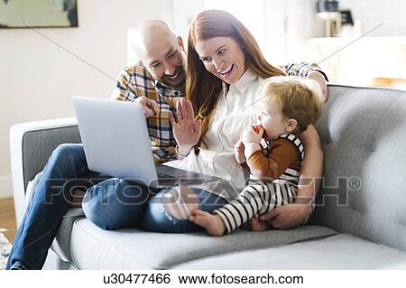 Stock Photograph - Family using laptop to video chat. Fotosearch