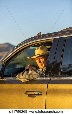 Stock Photo - Farmer wearing cowboy hat driving SUV. Fotosearch