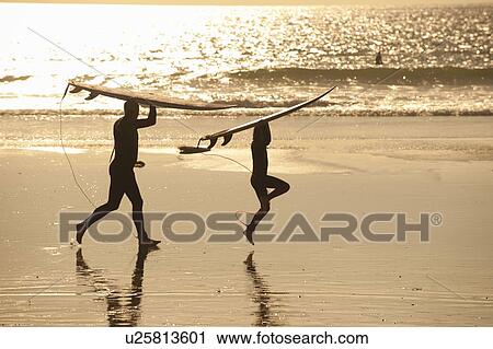 Father and son carrying surfboards on beach at sunset View Large Photo Image Stock Image - Father and son carrying surfboards on beach at sunset. Fotosearch