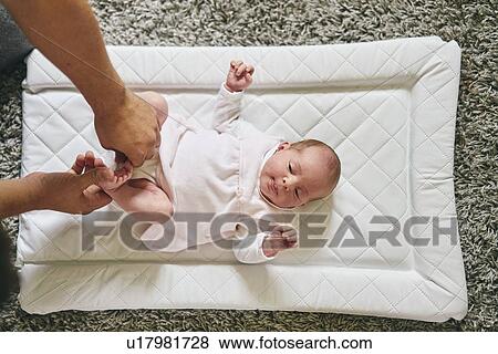 Stock Photo - Father changing baby's diaper at home. Fotosearch