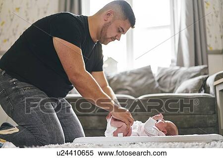 Father changing baby's diaper at home View Large Photo Image Stock Photography - Father changing baby's diaper at home. Fotosearch