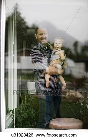 Stock Photograph - Father holding his daughter behind window. Fotosearch