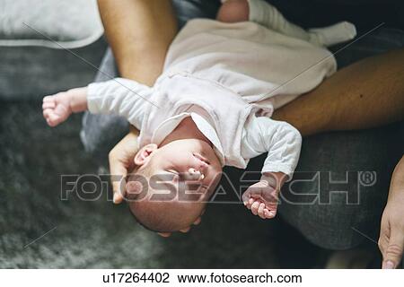 Stock Image - Father supporting head of baby on lap. Fotosearch