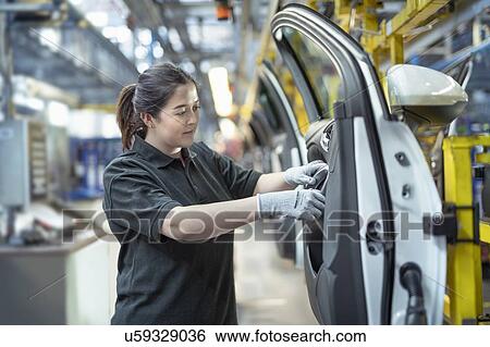 Stock Photograph - Female apprentice engineer assembling car doors in car factory. Fotosearch
