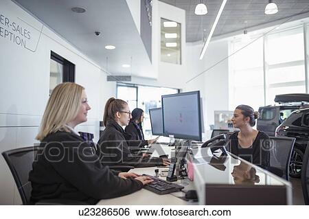 Stock Photograph - Female customer and staff at service desk in car dealership. Fotosearch