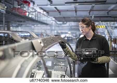 Stock Photograph - Female engineer testing car body in car factory. Fotosearch