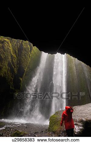 Stock Image - Female tourist looking up at waterfall, Selfoss, Arnessysla, Iceland. Fotosearch