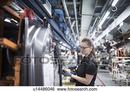 Stock Photograph - Female worker assembling car doors on production line in a car factory. Fotosearch