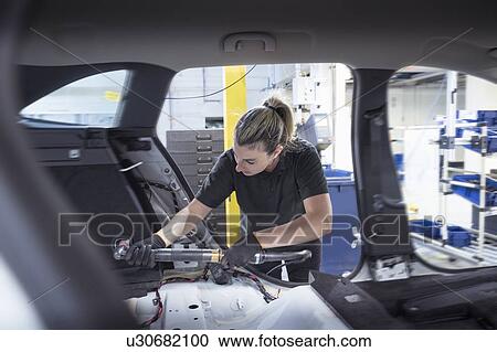 Stock Image - Female worker assembling car interior on production line in car factory. Fotosearch