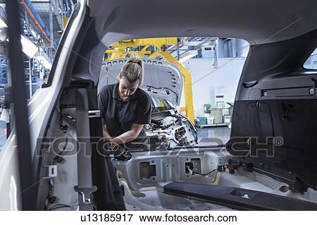 Stock Photo - Female worker assembling car interior on production line in car factory. Fotosearch