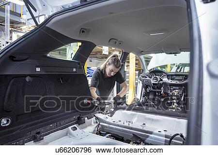 Stock Photograph - Female worker assembling car interior on production line in car factory. Fotosearch