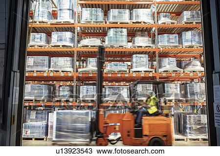 Stock Image - Fork lift truck driving past printed food packaging in storage in print factory. Fotosearch