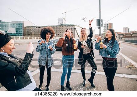 Stock Photo - Friends celebrating with confetti and soap bubbles in street, Milan, Italy. Fotosearch