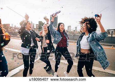 Stock Photo - Friends celebrating with confetti and soap bubbles in street, Milan, Italy. Fotosearch