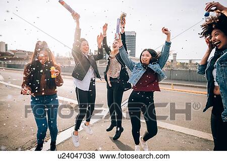 Stock Photo - Friends celebrating with confetti and soap bubbles in street, Milan, Italy. Fotosearch