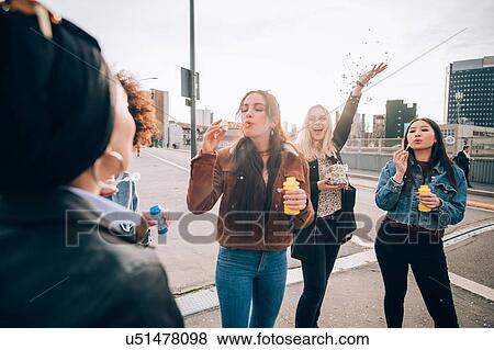 Friends celebrating with confetti and soap bubbles in street, Milan, Italy View Large Photo Image Stock Photo - Friends celebrating with confetti and soap bubbles in street, Milan, Italy. Fotosearch
