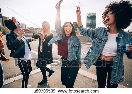 Stock Photo - Friends celebrating with confetti and soap bubbles in street, Milan, Italy. Fotosearch