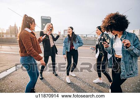 Picture - Friends dancing in street to smartphone music, Milan, Italy. Fotosearch