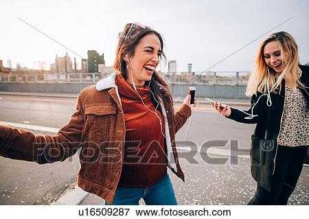 Stock Photo - Friends dancing in street to smartphone music, Milan, Italy. Fotosearch
